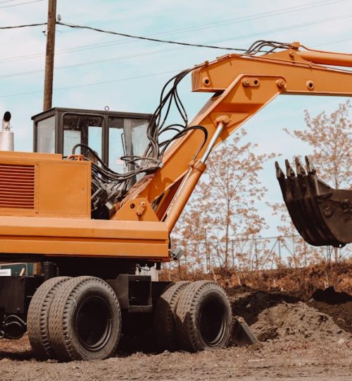 A yellow excavator at a rural construction site, ready for operation.