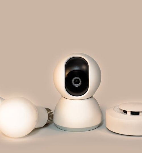 A collection of modern smart home gadgets including a CCTV camera, LED bulbs, and a smoke detector.